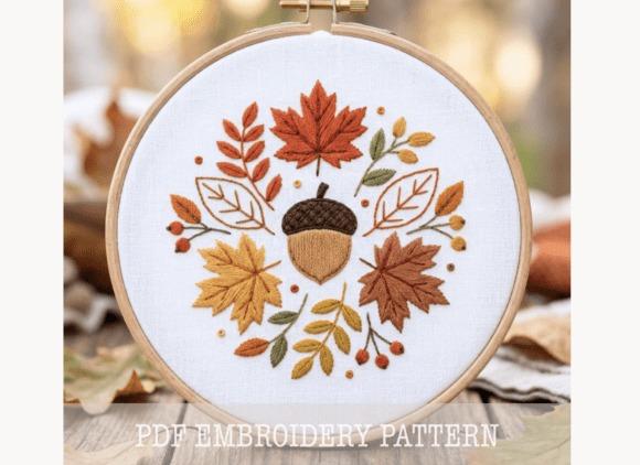 Fall embroidery patterns featuring an acorn and autumn leaves in a circular wreath design in a wooden hoop
