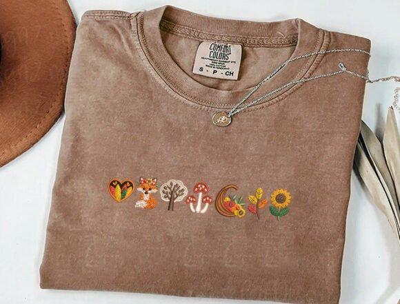 fall embroidery designs with fox, trees, mushrooms, leaves, and sunflower on brown shirt