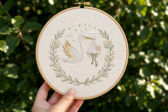 Baby blanket embroidery featuring a stork carrying a bundle surrounded by a floral wreath