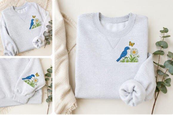Bluebird embroidery design on a light gray sweatshirt with a butterfly and flowers, showcasing bird embroidery designs