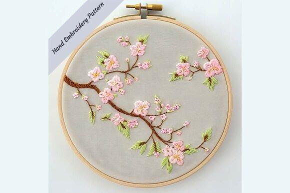 Hand embroidery designs featuring a cherry blossom branch with pink flowers and green leaves on fabric