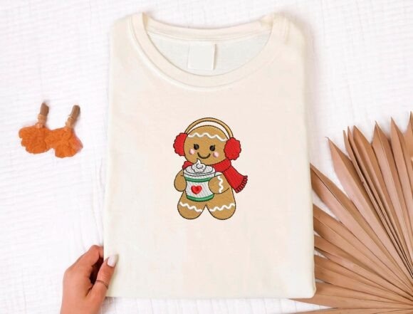 Etsy embroidery files for machine embroidery projects showing a gingerbread person with earmuffs and scarf holding a cup