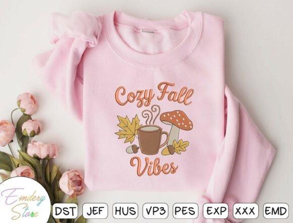 fall embroidery designs featuring a steaming coffee cup, colorful leaves, acorn, and mushroom on a pink sweatshirt
