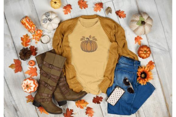 fall embroidery designs featuring a detailed pumpkin surrounded by autumn leaves on a mustard yellow shirt
