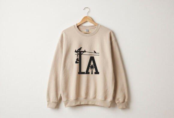 Beige hoodie with embroidered LA lettering, utility pole, palm tree, crows, and power lines design embroidered hoodie ideas