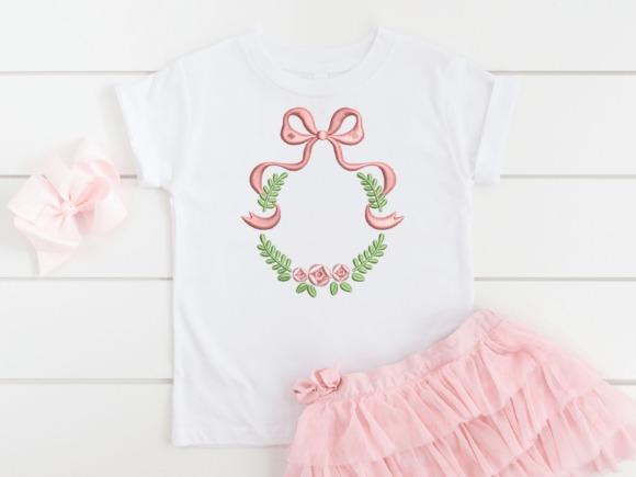 Monogram embroidery design with pink bow and floral wreath on white t-shirt