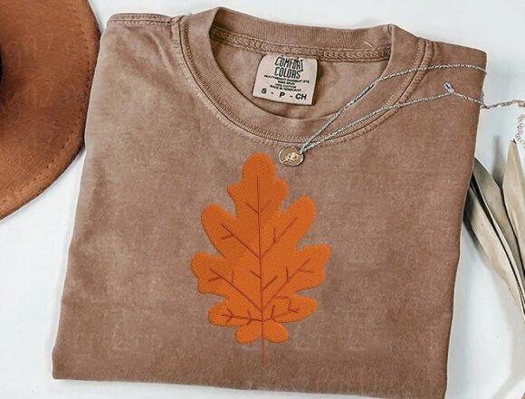 Brown shirt with orange fall leaf embroidery design resembling an oak leaf