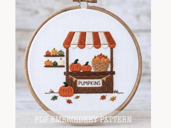 Fall embroidery patterns featuring a pumpkin stand with pumpkins and autumn leaves in an embroidery hoop