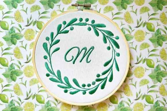 Round floral monogram machine embroidery with green leaves and letter M in center — name embroidery ideas