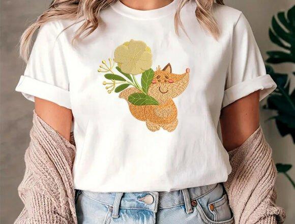 Animal embroidery of a woodland fox holding a yellow flower on a white t-shirt