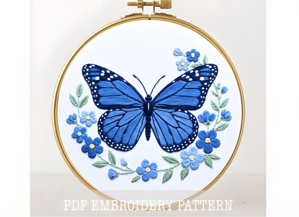 Blue monarch butterfly surrounded by blue flowers embroidered in hand embroidery patterns