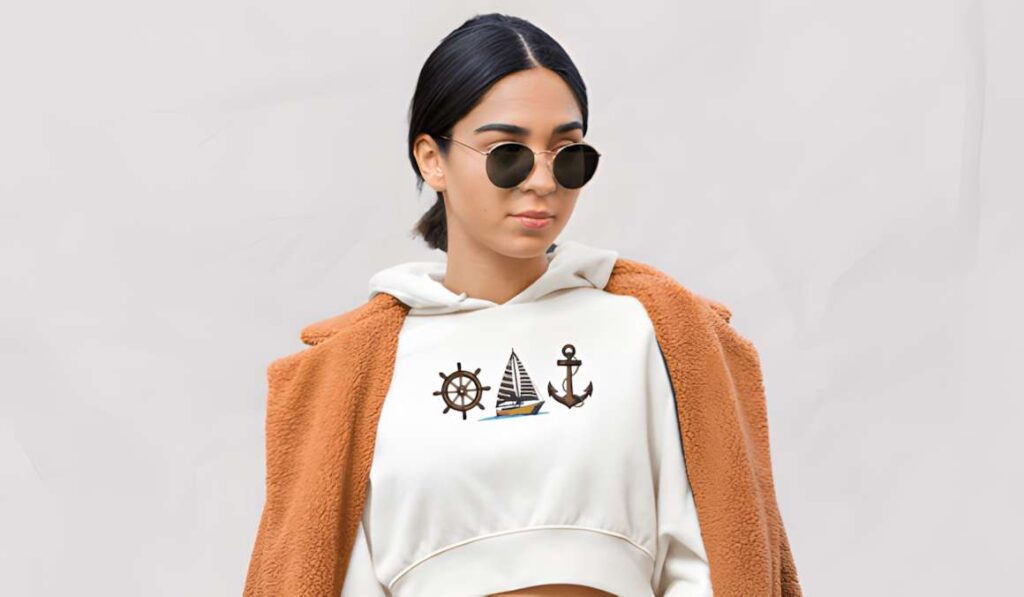 Woman wearing a white cropped hoodie with nautical machine embroidery designs for various styles including a ship wheel