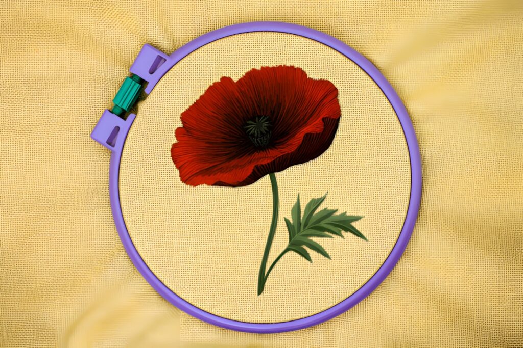 Hand embroidery patterns showing a detailed red poppy bloom stitched on yellow fabric in a purple hoop
